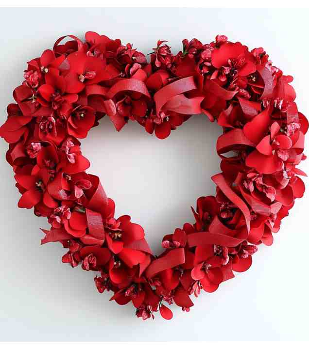 a heart shaped wreath made of red flowers